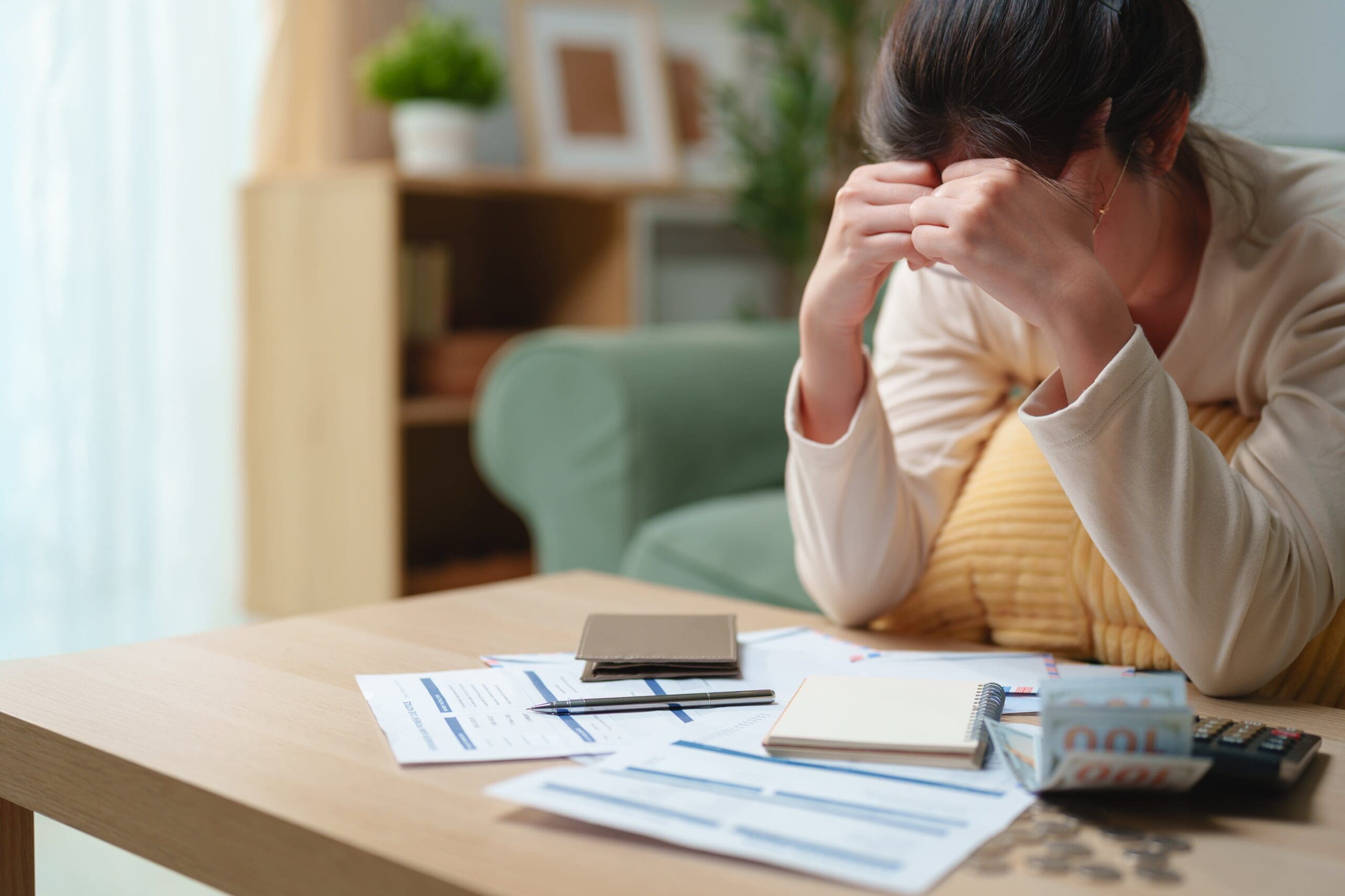 Stressed business owner reviewing financial documents while struggling with cash flow despite increasing revenue.